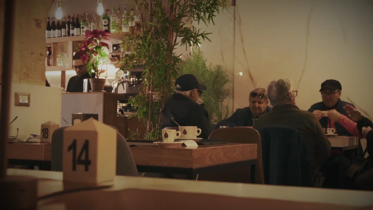 Interiér kaviarne Zi Caffè — v popredí drevené číslo stola 14, za ním stoly s hosťami a bar s fľašami v pozadí